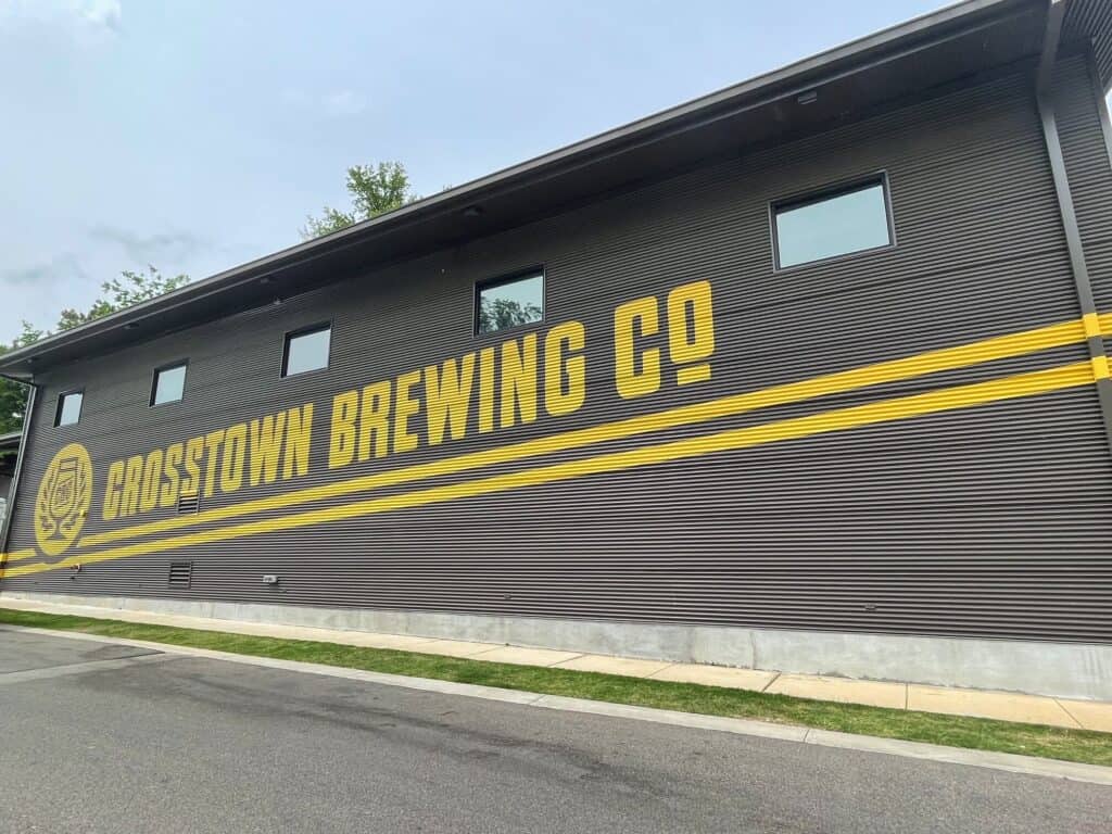 The front of Crosstown Brewing Co and its logo in yellow against a dark grey background in Memphis Crosstown Concourse.