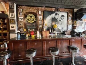 An old wooden bar with black and chrome bar stools with a picture of Elvis and other singers at the historic Sun Studio in Memphis.