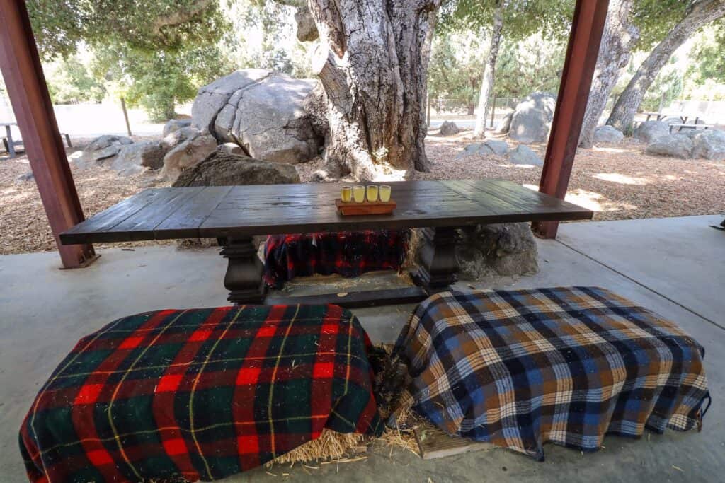 A wooden table with two bales of hay covered with blankets as benches at the Calico Cidery in Julian.