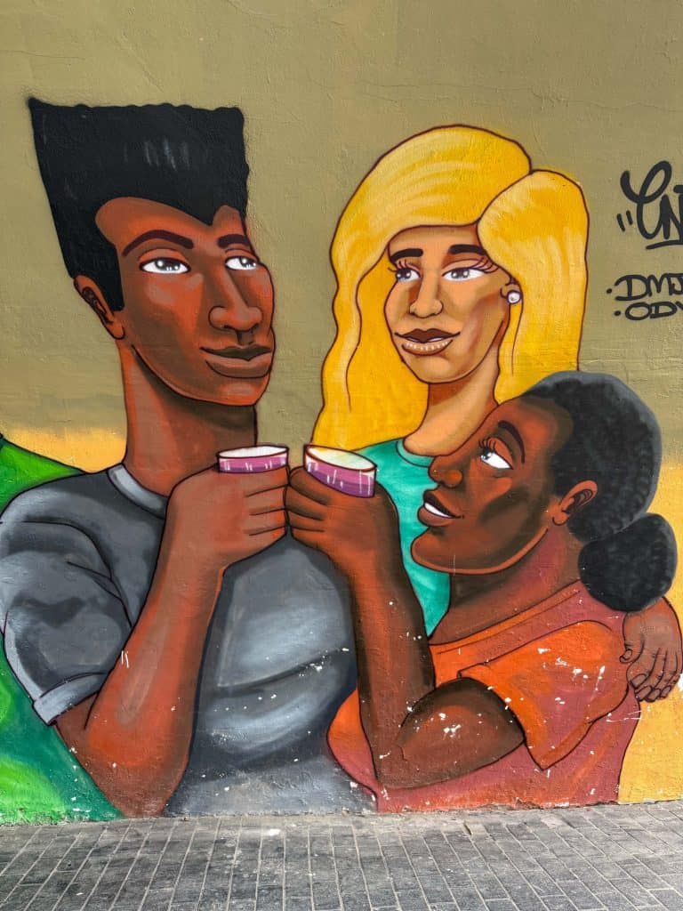 A colorful art mural of three Peruvian people enjoying something to drink on a street in Barranco neighborhood in Lima.