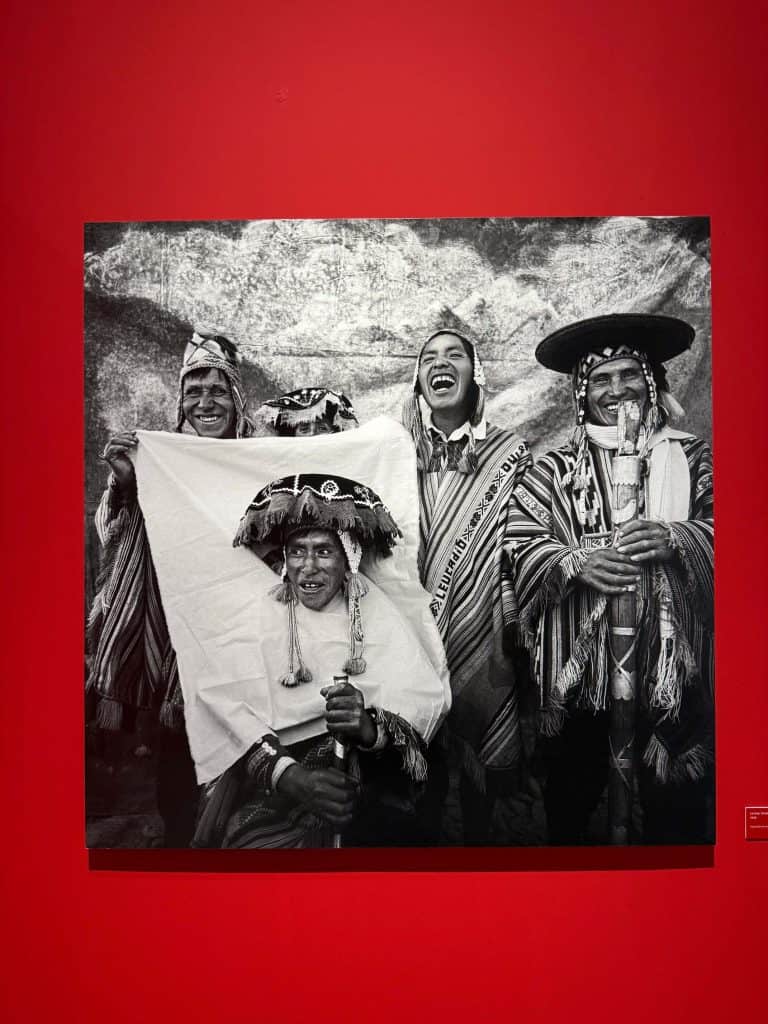 Large photo of Peruvian men dressed in traditional attire and laughing at the MAC museum in Lima.