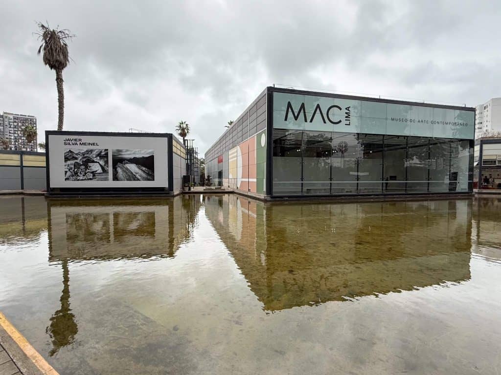 Front view of the modern MAC museum buildings with a shallow pond in front creating a reflection of the buildings.