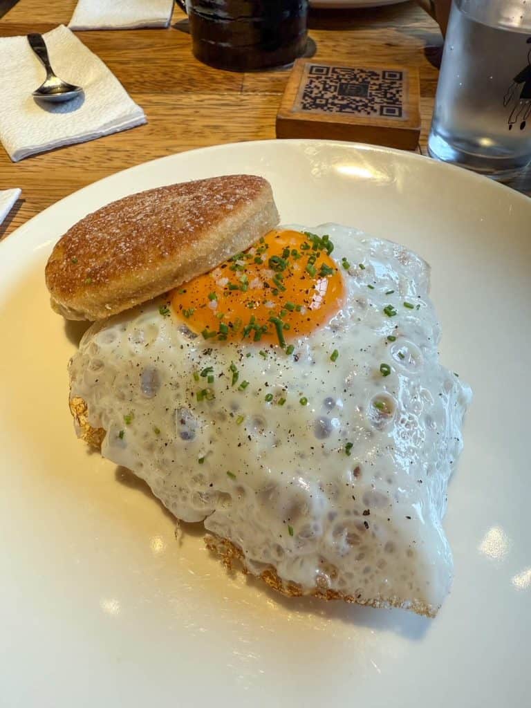 A delicious breakfast sandwich with a sunny side egg on top of handmade muffin with seasoning at Pan de Chola in Lima.
