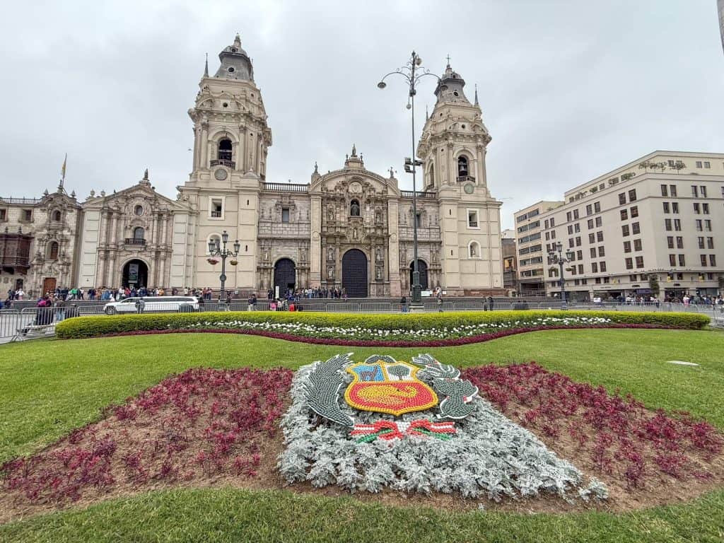 The front view of the Lima Cathedral in the historic district with flowers in the foreground.