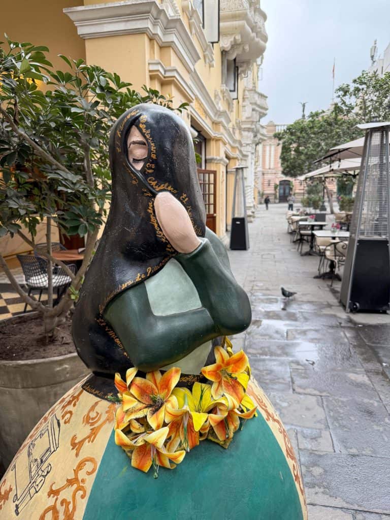 A close up view of a Las Tapadas Limenas (veiled woman) statue painted in vibrant colors, one of the best things to do in Lima as there are several to find in the historic district.