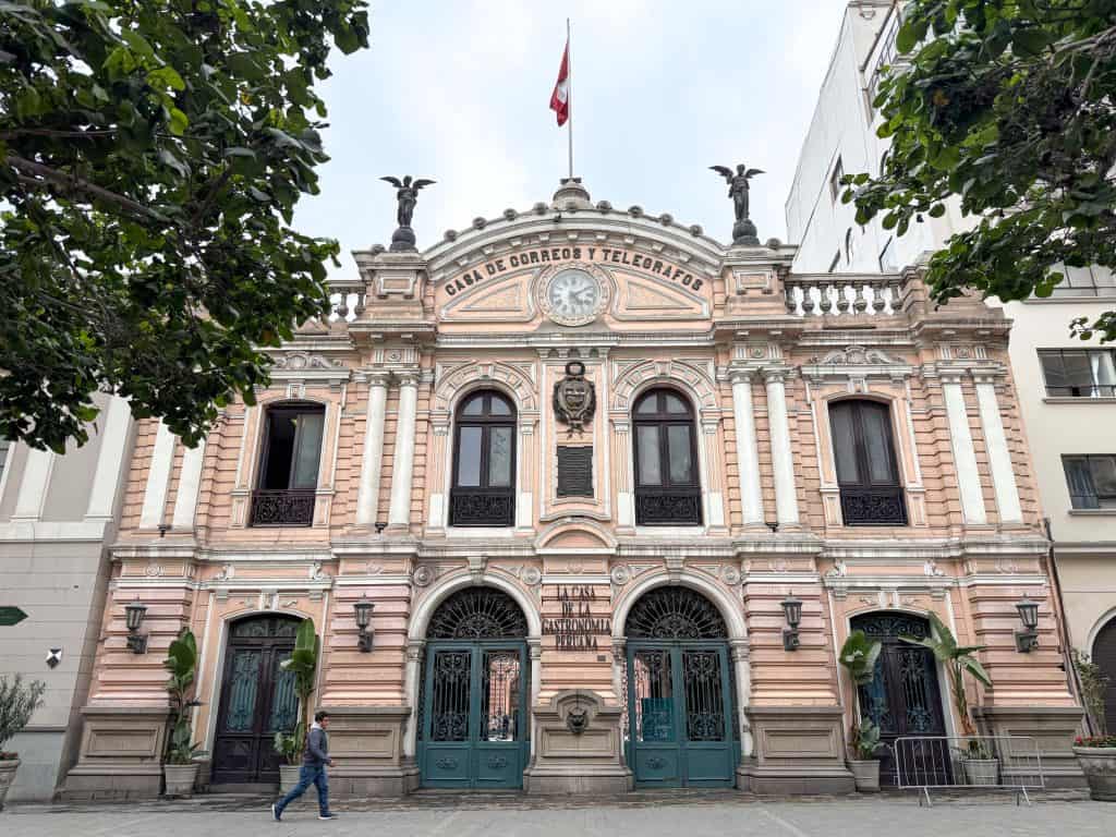 A beautiful historic building in Lima's historic district with its pink facade and ornate archiectural details with a flag on top.