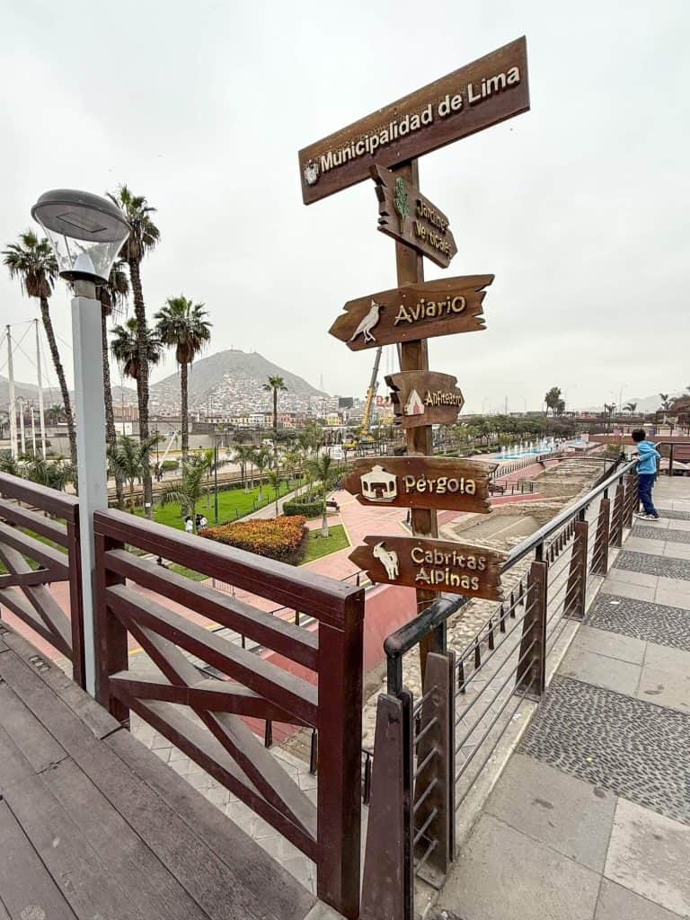 Standing on bridge above the ruins at Parque de la Muralla with views of the colorful houses on San Cristobal hill on a foggy and overcast day in Lima.