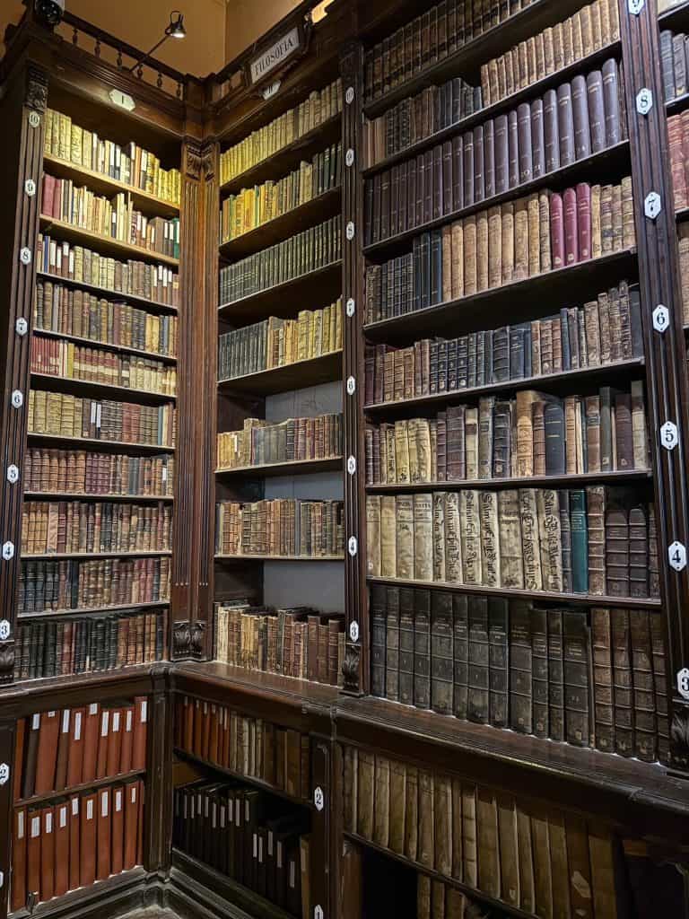 Rows of old and historic books in an old bookcase with the library at Santa Domingo Convent with low lighting.