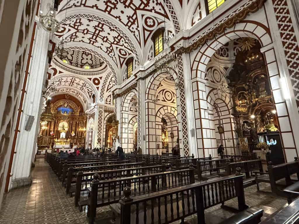Inside the gorgeous San Francisco church with its Spanish-Moorish architecture and design with white and a crimson red, low lighting, arched ceiling, and wooden pews.