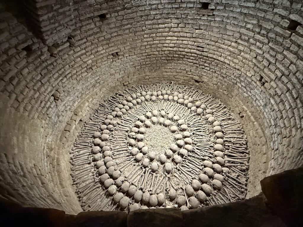 Looking down in a large cylindrical hole with several skulls and bones arranged in a series of circular patterns underneath the San Francisco church in Lima's historic center.