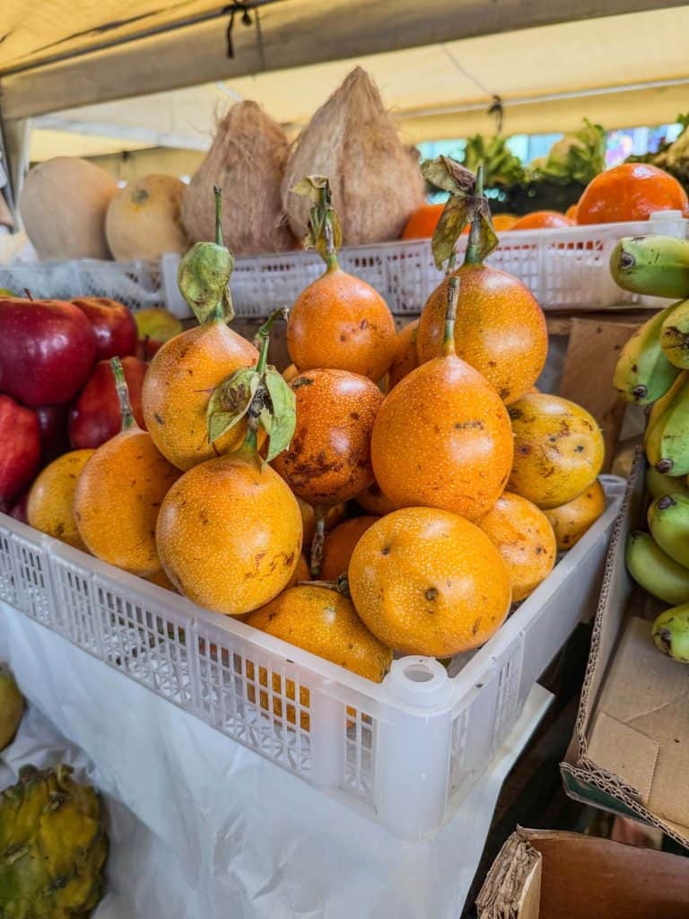 A box crate filled with orange fruit similar to a passion fruit at Mercado Surquillo in Lima.