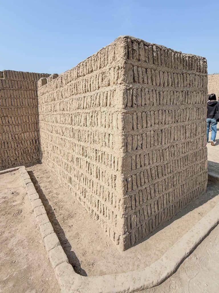 A rectangular section of the clay and adobe bricks stacked in vertical orientation like books on a shelf at the Huaca Pucllana ruins in Lima.