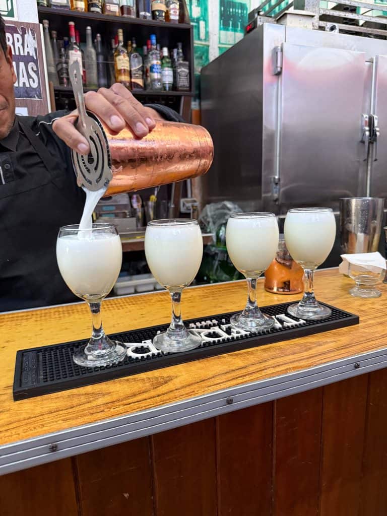 A bartender making 4 Pisco Sour cocktails at a bar in Lima, Peru.