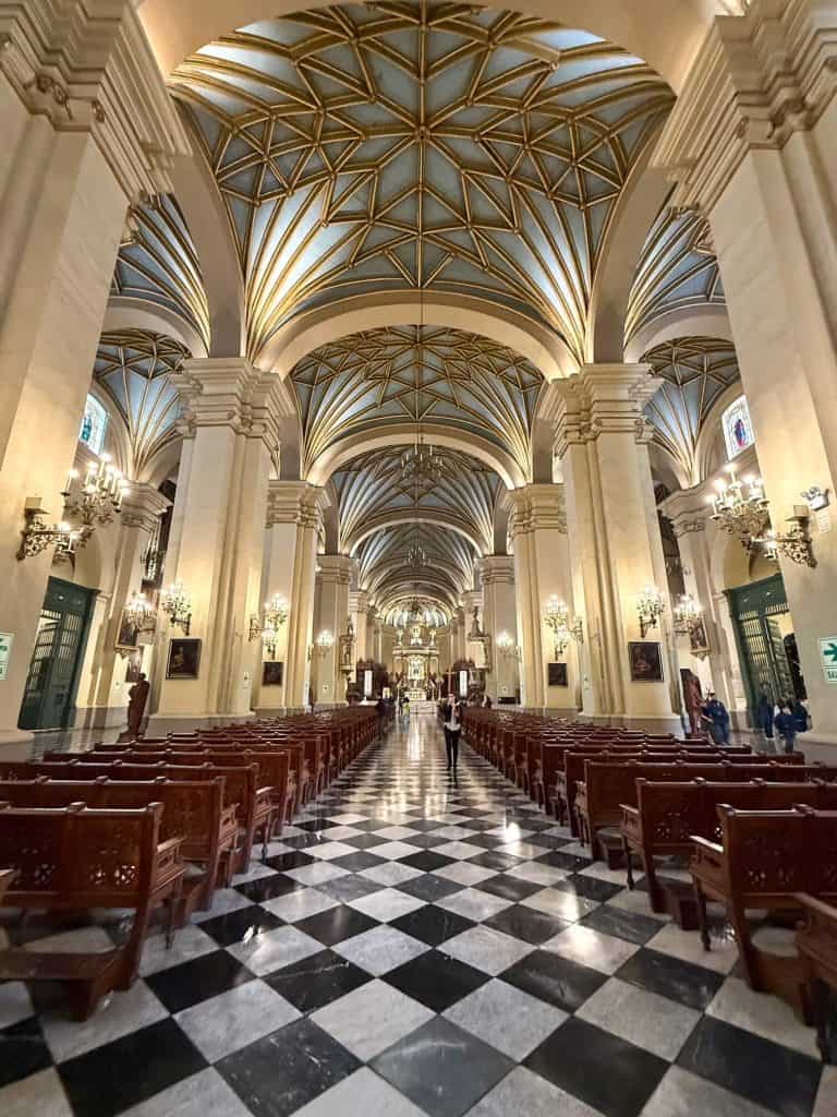 Interior view of the Lima Cathedral with its stunning arched ceilings, architecture, black and white checkered floor and wooden pews.