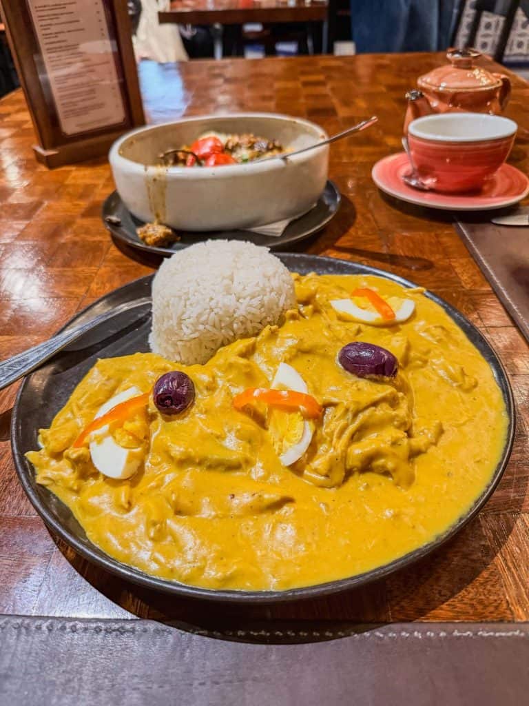 A delicious plate of Aji de Gallina, a traditional Peruvian dish with its yellow colored sauce over rice with chicken, hard boiled egg and olives.