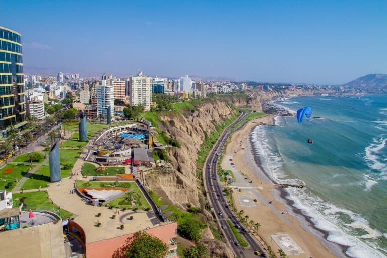Aerial view of Lima's coastline with hotels and buildings of Miraflores overlooking the Pacific Ocean from the top of the cliffs.