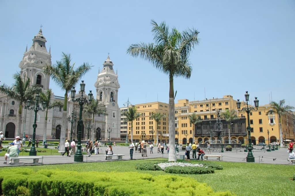 Plaza Mayor (main square) in Lima's historic district with palm trees, water fountain, and the cathedral on the far side.
