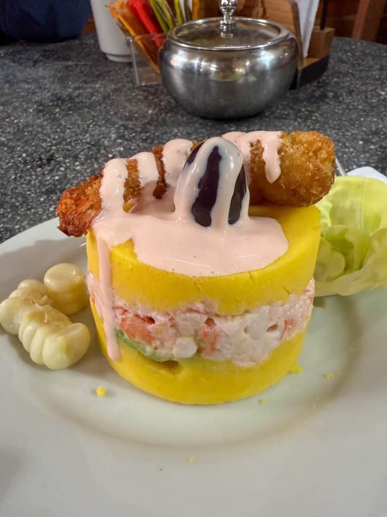 A Peruvian dish called Causa on a plate that is layered with cold mash potatoes and a shrimp mayo layer in Lima, Peru.