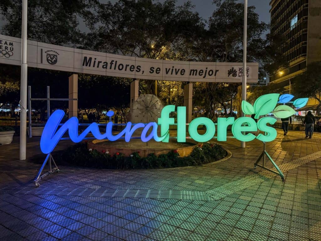 A brightly lit Miraflores sign in blue and green colors at night at Kennedy Park in Miraflores neighborhood of Lima, Peru.