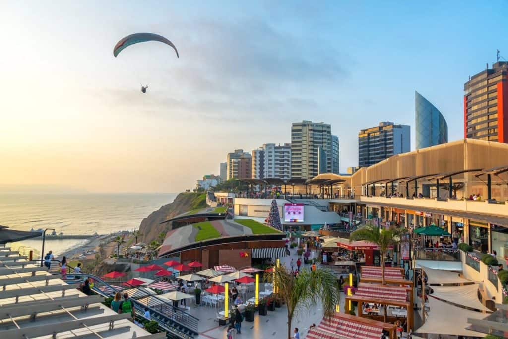 Outdoor Larcomar shopping center with view of the Pacific Ocean, paraglider, and buildings of Miraflores in Lima, Peru.