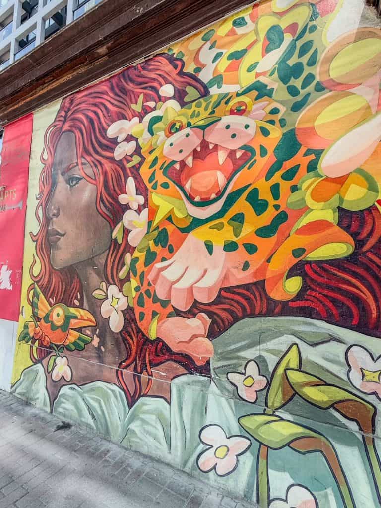 An art mural of a Peruvian woman with red wavy hair and a leopard sitting on her shoulder with flowers, one of the best things to do in Miraflores, Lima.